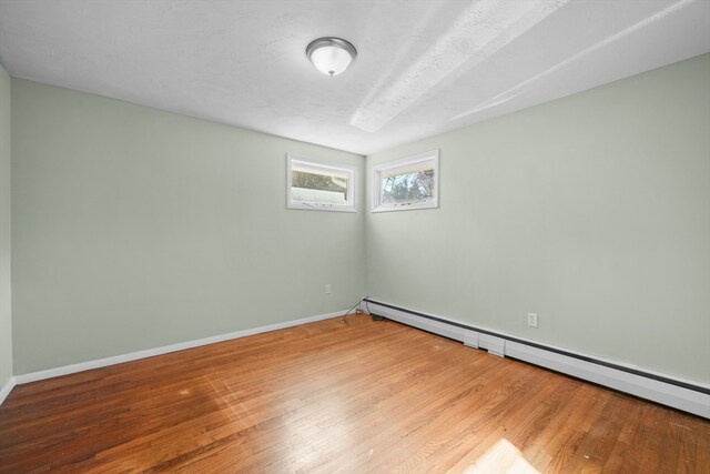 spare room featuring hardwood / wood-style flooring, a textured ceiling, and a baseboard heating unit