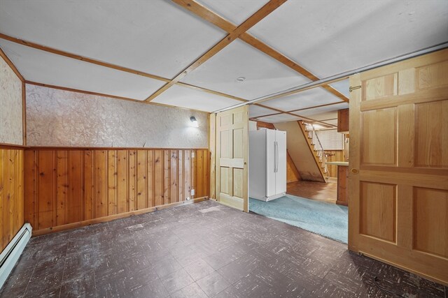 additional living space with wooden walls and a baseboard heating unit