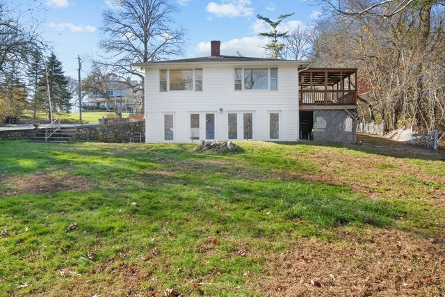 rear view of house featuring a wooden deck and a yard