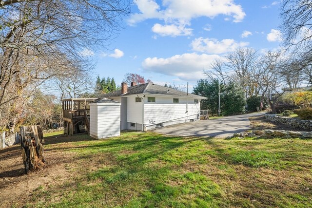 view of side of home featuring a yard and a storage unit