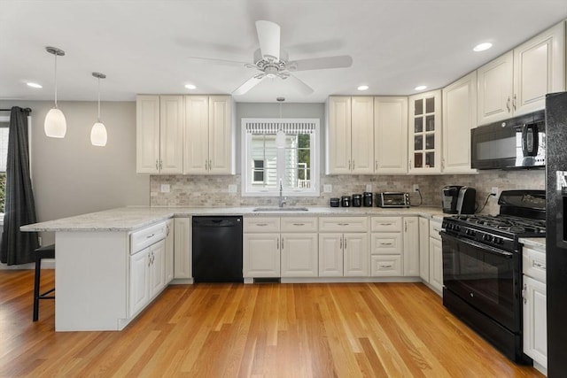 63 Prospect St Unit 2, Woburn, MA 01801 - kitchen featuring black appliances, a sink, a peninsula, a breakfast bar, and ceiling fan