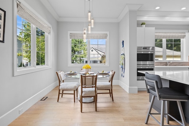 dining room featuring light hardwood / wood-style flooring, crown molding, and a wealth of natural light