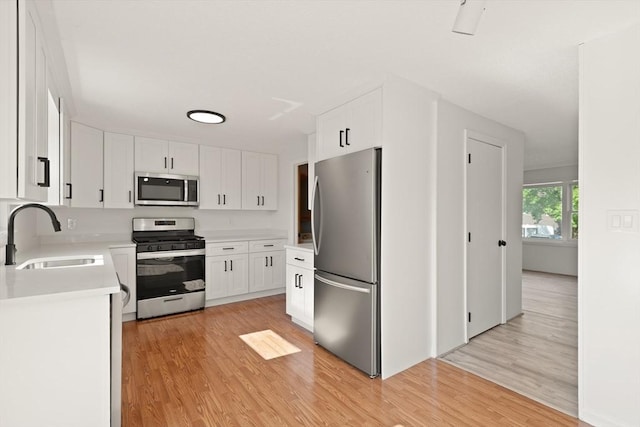 126 Willard St Unit D, Lowell, MA 01850 - kitchen featuring appliances with stainless steel finishes, a sink, light wood-style flooring, light countertops, and white cabinets