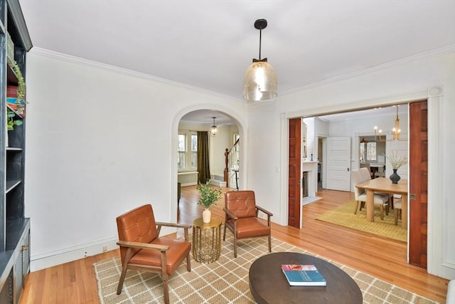 living area with wood-type flooring, crown molding, and a notable chandelier