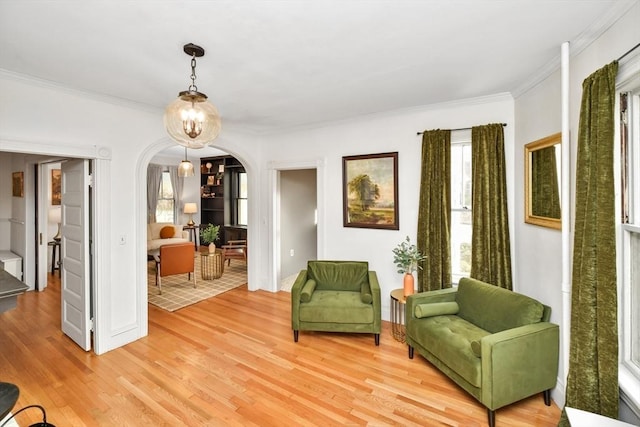 living area featuring a chandelier, light wood-type flooring, and ornamental molding