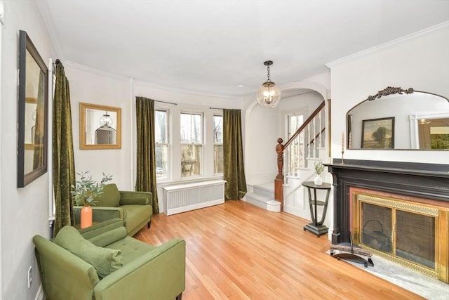 sitting room with hardwood / wood-style floors, a notable chandelier, crown molding, and radiator