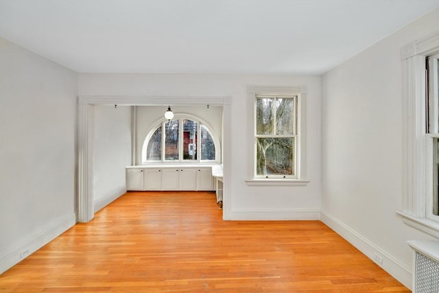 spare room featuring radiator heating unit and light hardwood / wood-style flooring