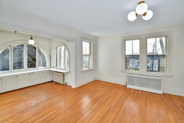 interior space featuring radiator, light hardwood / wood-style floors, and a notable chandelier