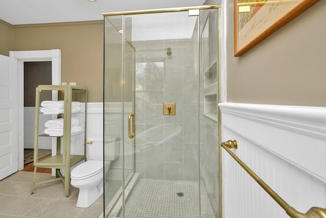 bathroom featuring toilet, tile patterned floors, and a shower with door