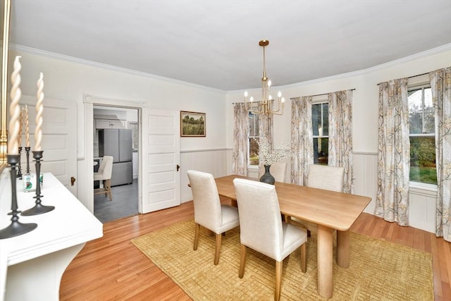 dining space with light hardwood / wood-style flooring and ornamental molding