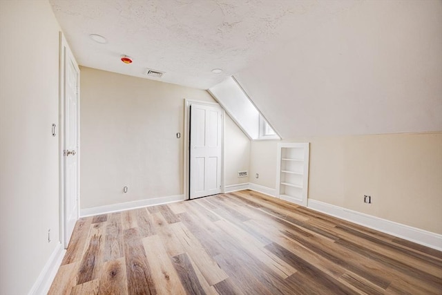 6 Nemasket St, Middleboro, MA 02346 - bonus room featuring a textured ceiling, vaulted ceiling, visible vents, light wood finished floors, and baseboards