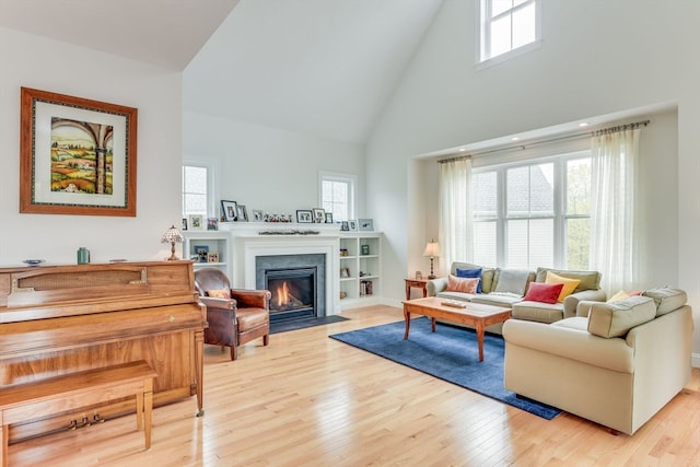 living room with a healthy amount of sunlight, light hardwood / wood-style flooring, and high vaulted ceiling