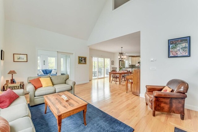 living room with light hardwood / wood-style flooring, an inviting chandelier, and high vaulted ceiling