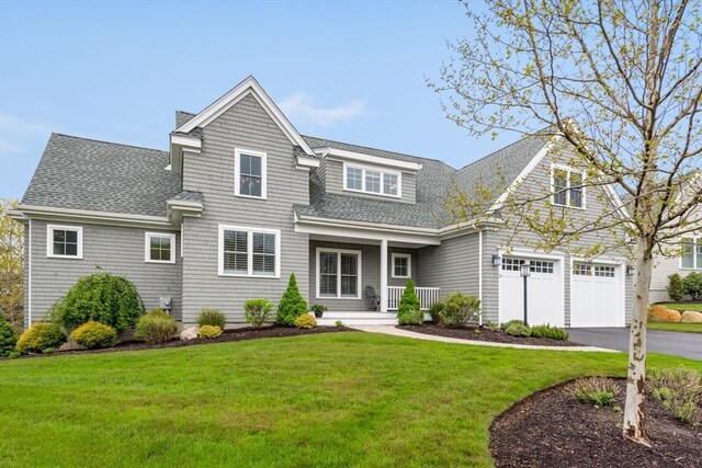 view of front of property featuring a front yard, a garage, and a porch