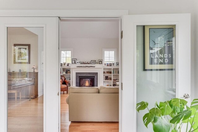 living room with a high end fireplace and light hardwood / wood-style flooring