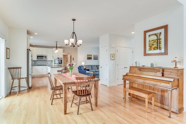 dining area with light wood-type flooring and an inviting chandelier