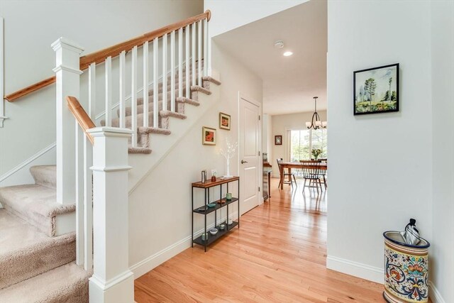 staircase with hardwood / wood-style floors and an inviting chandelier