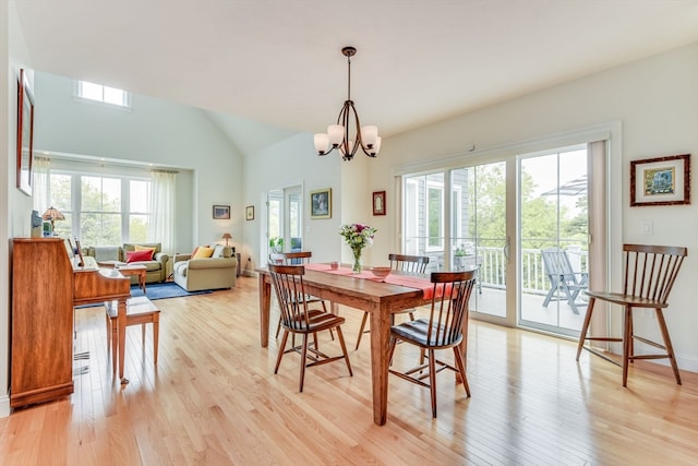 dining area featuring light wood-type flooring, vaulted ceiling, and an inviting chandelier