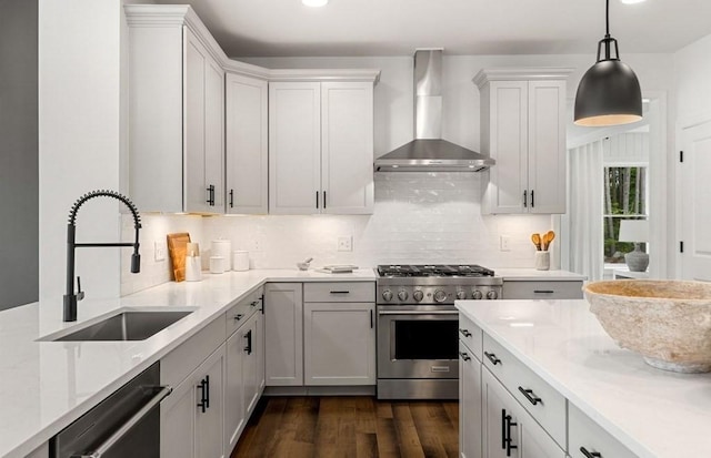 kitchen with dark wood finished floors, high end stainless steel range, a sink, wall chimney range hood, and dishwasher