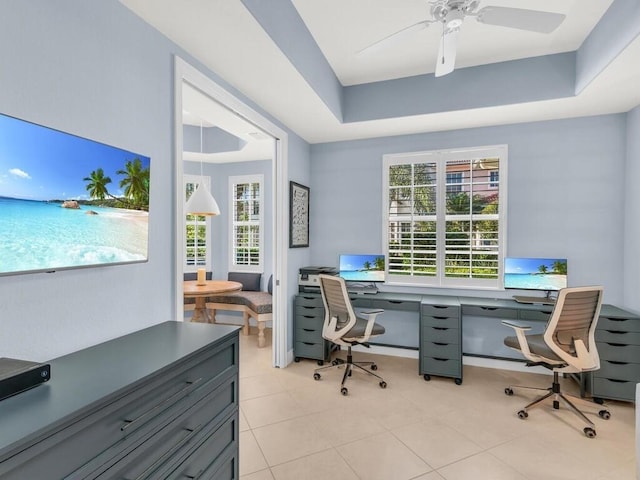 office featuring a tray ceiling, ceiling fan, and light tile patterned floors