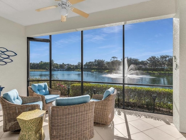 sunroom featuring ceiling fan and a water view