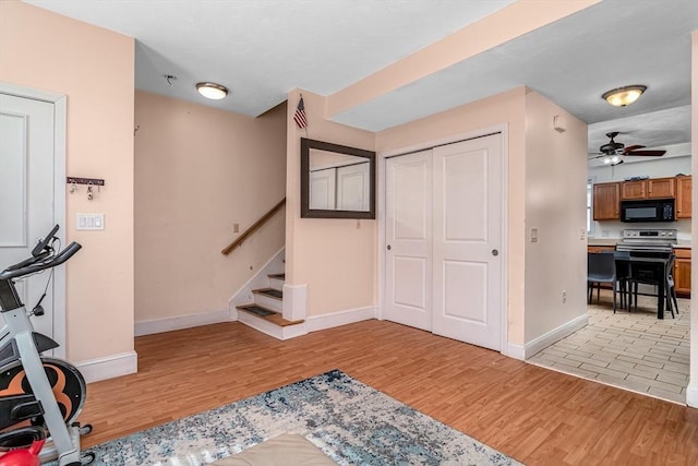 interior space with light wood-style flooring, baseboards, stairs, and ceiling fan