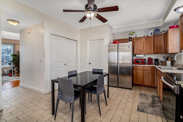 kitchen featuring brown cabinetry, stainless steel appliances, light countertops, and a sink