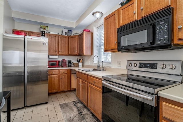 kitchen with a sink, stainless steel appliances, brown cabinetry, and light countertops