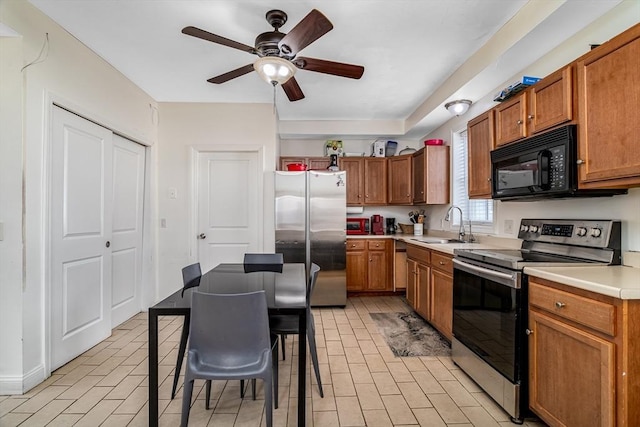 kitchen featuring light countertops, brown cabinetry, stainless steel appliances, a ceiling fan, and a sink