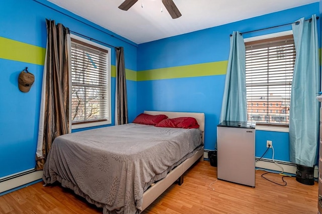 bedroom with ceiling fan, light wood-style flooring, and a baseboard radiator