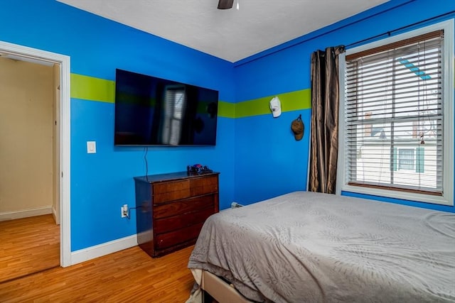 bedroom with a ceiling fan, wood finished floors, and baseboards