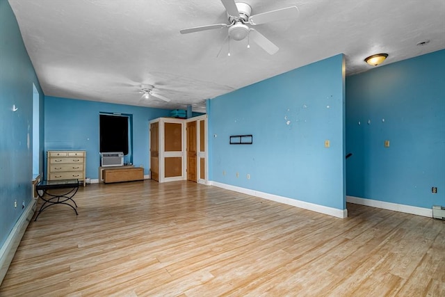 interior space featuring cooling unit, baseboards, wood finished floors, and a ceiling fan