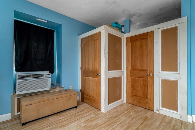 unfurnished bedroom with cooling unit and wood finished floors