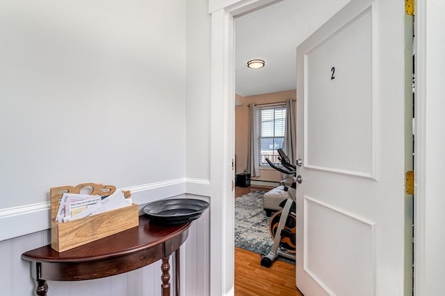 hall featuring a baseboard heating unit and wood finished floors