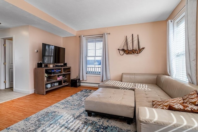 living area featuring a baseboard heating unit, baseboards, and wood finished floors