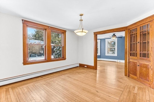 unfurnished dining area with a baseboard radiator and light hardwood / wood-style floors