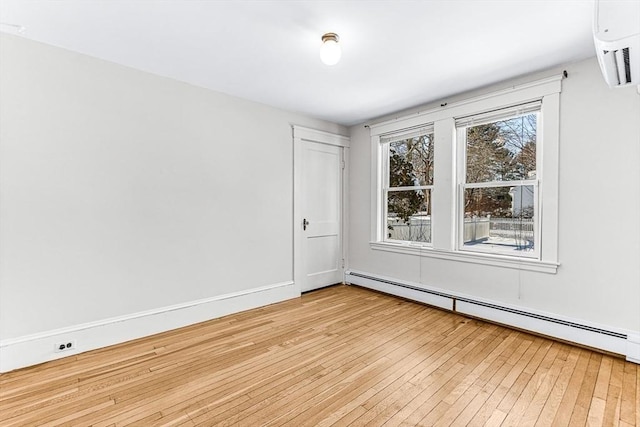 empty room with baseboard heating and light hardwood / wood-style floors