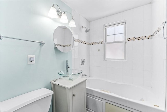 full bathroom featuring vanity, tiled shower / bath, and toilet