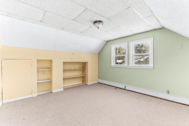 additional living space featuring lofted ceiling, a baseboard heating unit, built in features, and carpet flooring