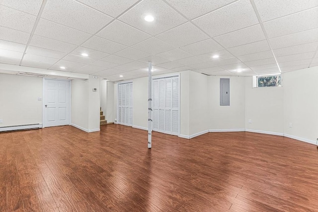 basement with a baseboard heating unit, hardwood / wood-style flooring, and electric panel