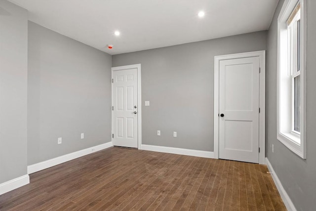 empty room with plenty of natural light, wood finished floors, baseboards, and recessed lighting