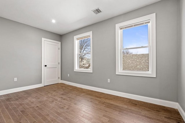 unfurnished room featuring baseboards, wood finished floors, and recessed lighting