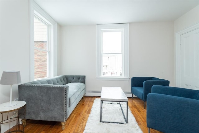 sitting room featuring healthy amount of natural light, baseboard heating, and wood finished floors