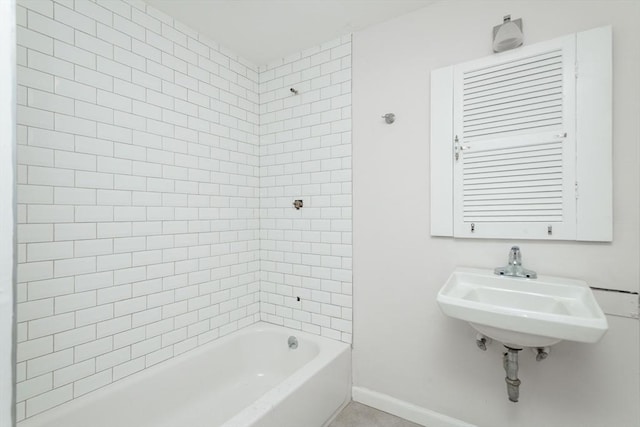 bathroom with baseboards, shower / bath combination, and a sink