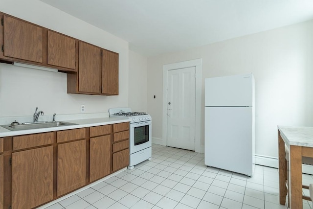 kitchen featuring white appliances, a sink, light countertops, a baseboard heating unit, and light tile patterned flooring