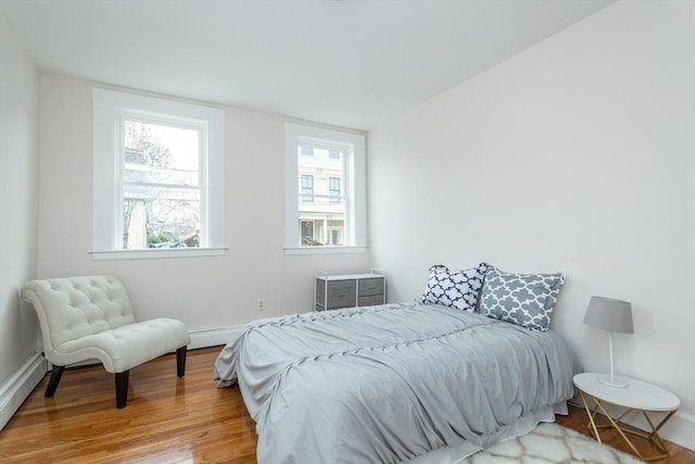 bedroom featuring wood finished floors, baseboards, and baseboard heating