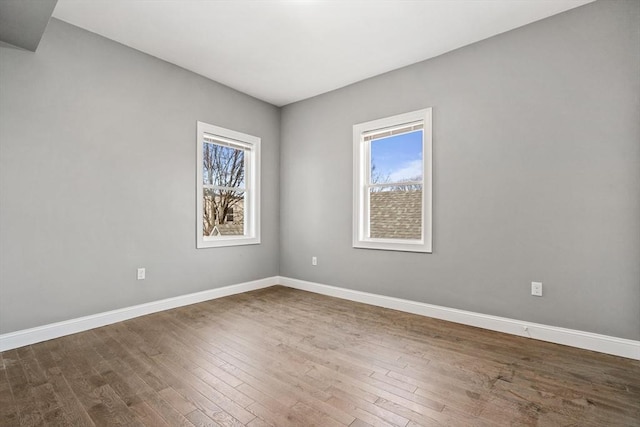 empty room featuring plenty of natural light, dark wood-type flooring, and baseboards