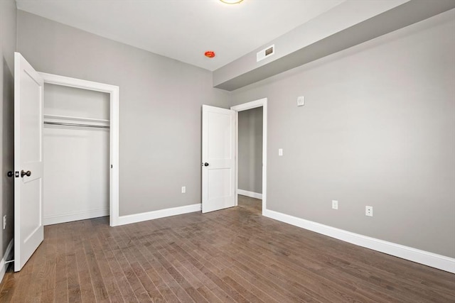 unfurnished bedroom with wood finished floors, baseboards, and a closet