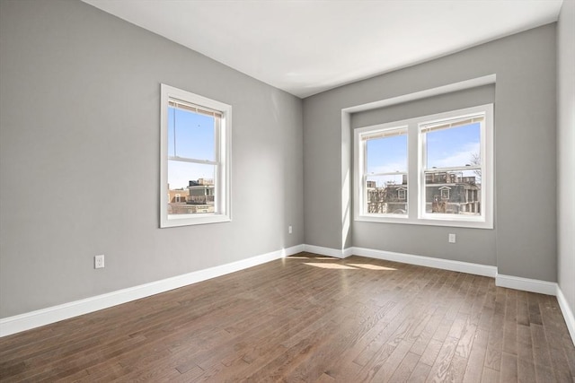 empty room with baseboards and dark wood-type flooring