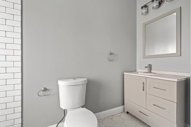 bathroom with toilet, baseboards, vanity, and tile patterned floors